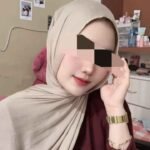 Woman in hijab wearing gold watch.